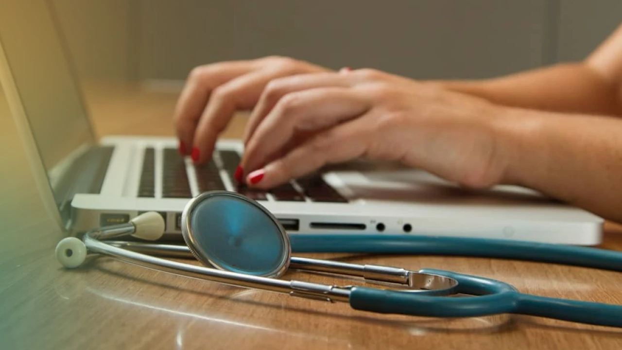 Profissional de saúde ou estudante de medicina usando laptop com estetoscópio ao lado, simbolizando tecnologia na medicina, telemedicina e saúde digital.
