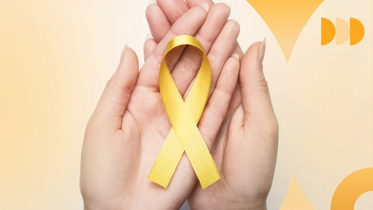 Mãos segurando laço amarelo, símbolo de conscientização sobre câncer infantil, esperança e solidariedade na luta contra doenças infantis.
